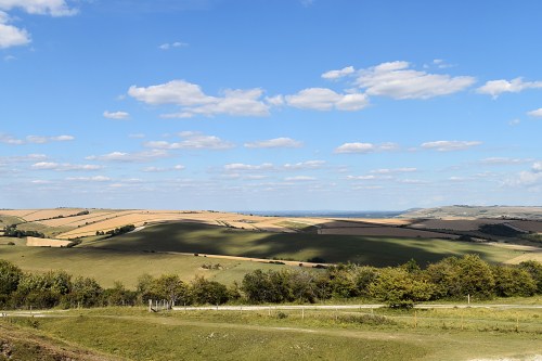 Rolling green hills under blue sky with fluffy white clouds