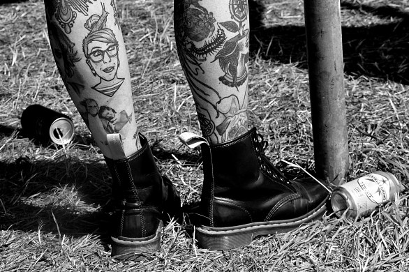 Someone with heavily tattooed legs wearing DM boots, shot from the shins down