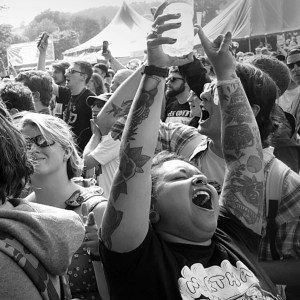 Festival crowd shot, girl at the front has her arms in the air and is singing along to the music
