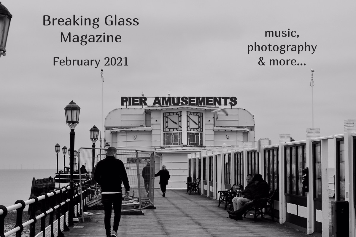Black and white shot of people taking a socially distanced walk along Worthing Pier, the closed amusement arcade is straight ahead