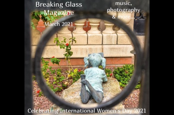 A statue of a girl lying on her stomach reading a book, taken through an iron gate, cover shot for Breaking Glass Magazine March 2021